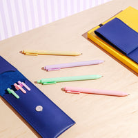 The PK Vivid Gel Pastel Pens displayed on a table and with a pencil case and book.